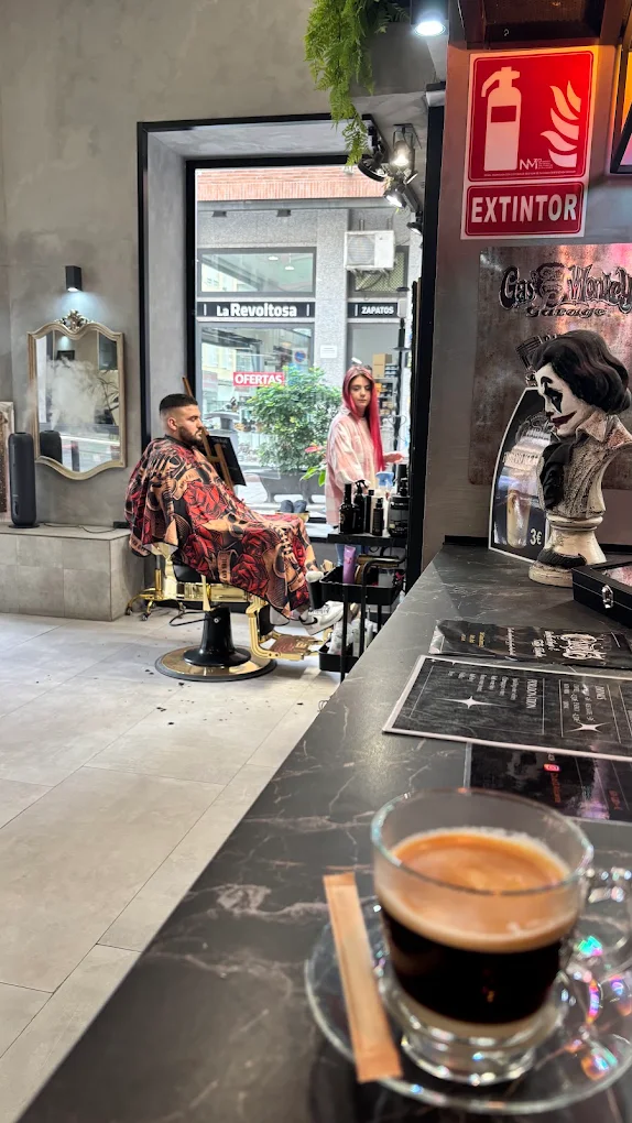 Cliente en el sillón de barbero junto a la barra del local
